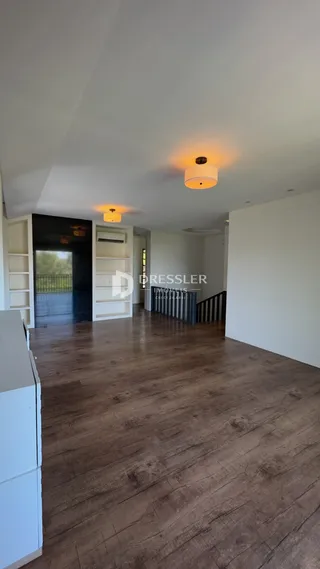 Ambiente interno com piso de madeira e paredes brancas.