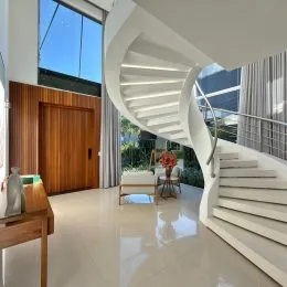 Hall de entrada com escadaria branca e piso claro.