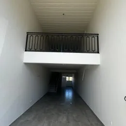 Corredor interno com paredes brancas e teto alto.
