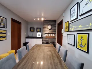 Foto de um ambiente interno com mesa de jantar de madeira e armários brancos.