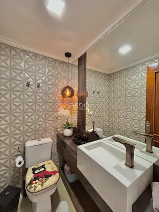 Banheiro moderno com revestimento geométrico nas paredes e bancada dupla.