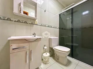 Foto de um banheiro com revestimento cerâmico e box de vidro.