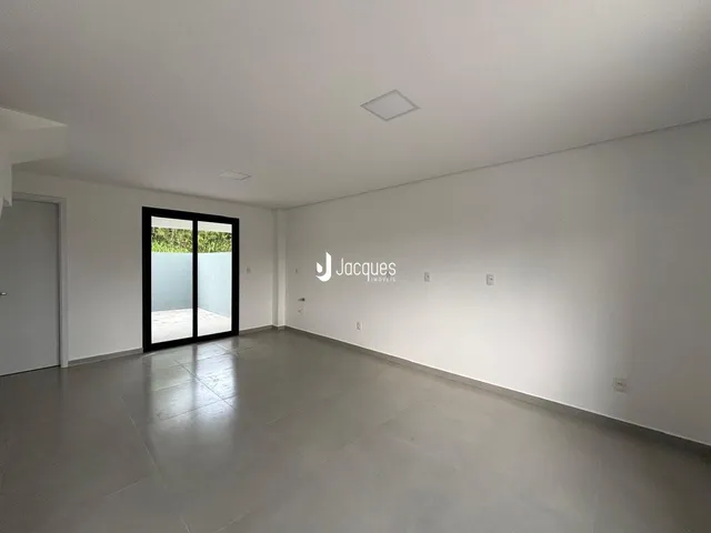 Sala de estar ampla com porta de vidro que dá acesso ao exterior.