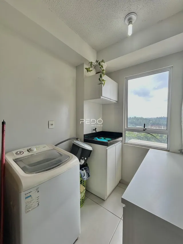Foto de uma área interna com máquina de lavar roupa e janela.