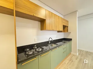 Cozinha com armários de madeira e bancada escura.