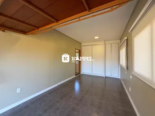 Foto de uma sala ampla com piso de concreto e armários brancos.
