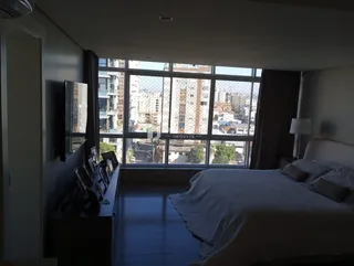 Quarto com vista para a cidade através de uma grande janela.