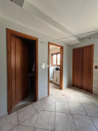Passagem interna de uma residência com portas de madeira e piso de cerâmica.