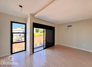 Vista interna de uma sala com piso de madeira e porta de vidro.
