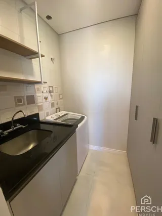 Uma cozinha com bancada escura e armários brancos é visível na imagem.