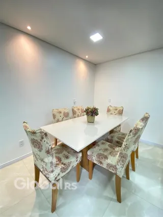 Foto de uma sala de jantar com mesa branca e cadeiras decorativas.