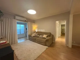 Sala de estar com sofá e piso de madeira em um imóvel no Brasil.