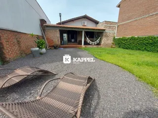 Vista externa da residência com fachada de tijolos e área de entrada coberta.