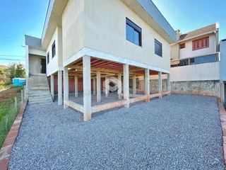 Fachada de uma casa em construção com área externa de cascalho.