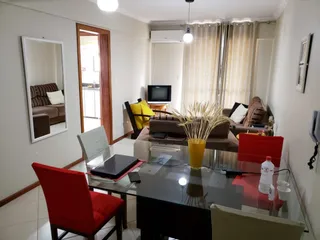 Sala de estar com mesa de vidro e cadeira vermelha em um imóvel.