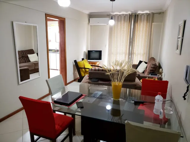 Sala de estar com mesa de vidro e cadeira vermelha em um imóvel.