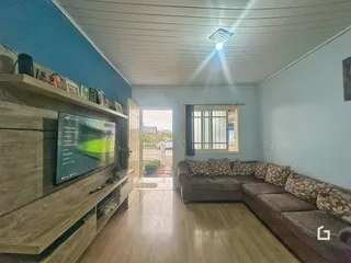 Sala de estar com sofá e televisão em um imóvel.
