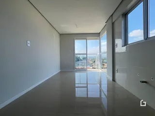 Sala ampla com piso claro e grandes janelas de vidro.