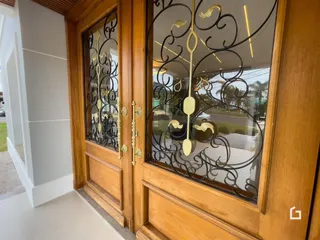 Entrada da residência com portas de madeira e ferro forjado.