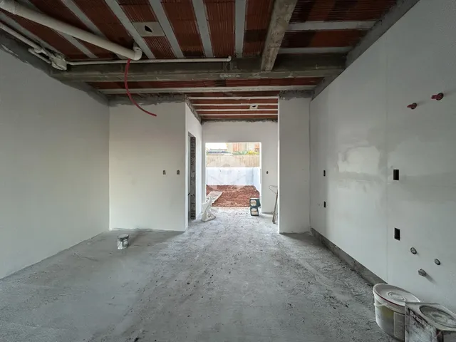 Interior de um espaço em construção com paredes de concreto aparente.