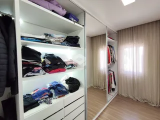 Armário branco com roupas organizadas no quarto.