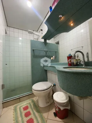 Foto de um banheiro com revestimento cerâmico e box de vidro.