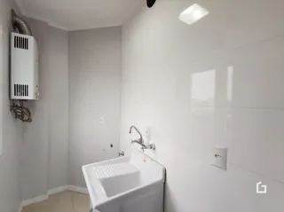 Foto de um banheiro com pia e revestimento branco.