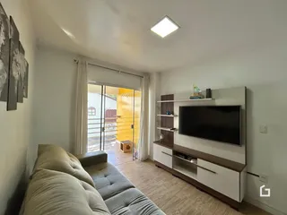 Sala de estar com sofá e portas de vidro que dão acesso ao exterior.