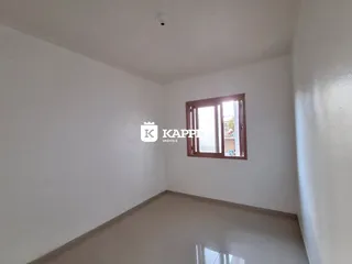 Uma foto de um corredor interno com paredes brancas e piso claro.