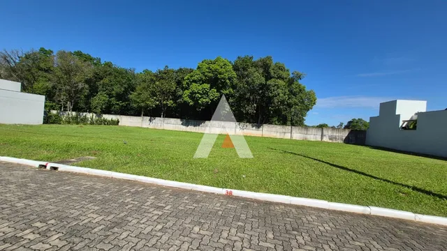 Vista externa de um terreno com gramado verde e cerca branca.