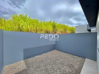 Fachada externa de uma propriedade com vegetação verde ao fundo.