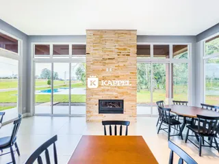 Sala de estar com grandes portas de vidro que oferecem vista para um jardim e piscina.