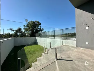 Vista da fachada de uma propriedade com muro de vidro e jardim.