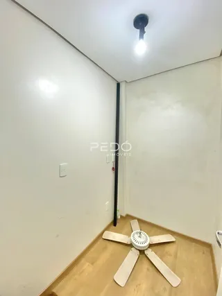 Vista de um corredor interno com paredes brancas e piso de madeira clara.