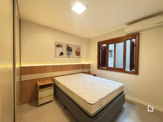 Quarto com cama e janela de madeira.