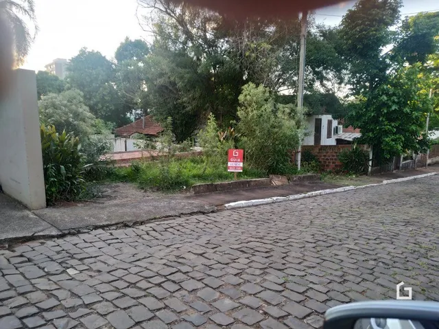 Vista da fachada de uma propriedade com calçamento de paralelepípedos e vegetação ao fundo.