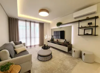 Sala de estar com sofá e televisão montada na parede.