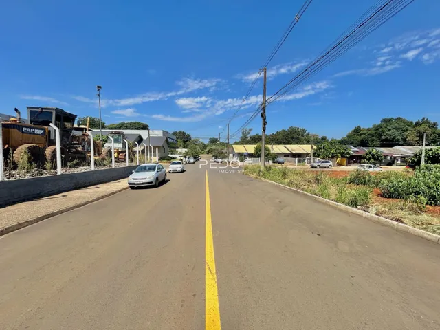 Vista da rua em Lajeado, Brasil, com veículos e vegetação ao longo da via.