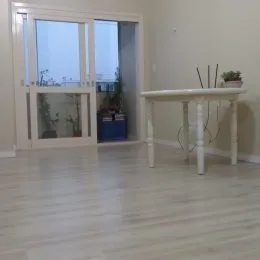Sala de estar com piso de madeira e grandes janelas.