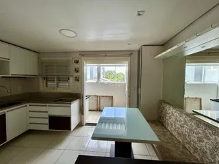 Interior de uma sala de estar com cozinha em um imóvel no Brasil.