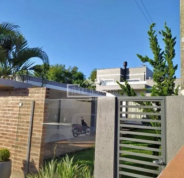 Vista da fachada de uma residência com muro de tijolos e cerca de vidro.