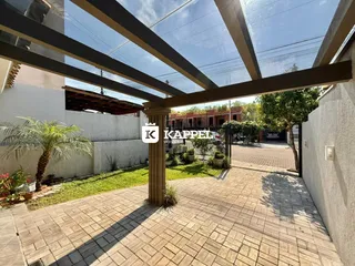 Uma área externa pavimentada com pergolado e vegetação é visível na propriedade.