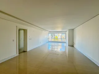 Corredor interno de uma residência com piso claro e grande janela.