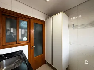 Interior de uma cozinha com armários de madeira e paredes brancas.