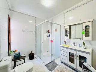 Foto de um banheiro com box de vidro e armário branco.