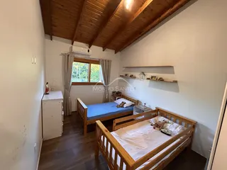 Quarto com cama de madeira e janela com cortinas na sala.