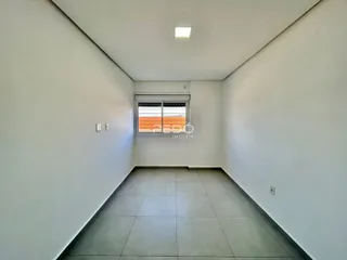 Corredor interno de um imóvel com paredes brancas e piso de cerâmica.