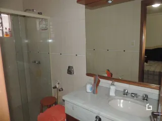 Foto de um banheiro com revestimento cerâmico e bancada branca.
