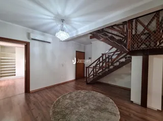 Ambiente interno com piso de madeira e escadaria no interior de uma residência.