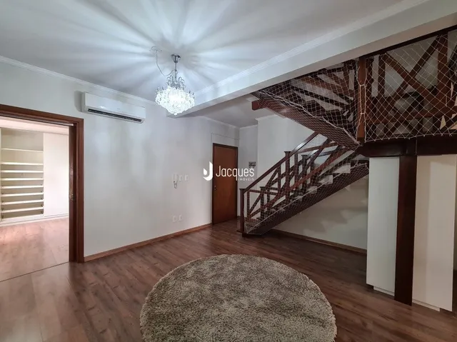 Ambiente interno com piso de madeira e escadaria no interior de uma residência.